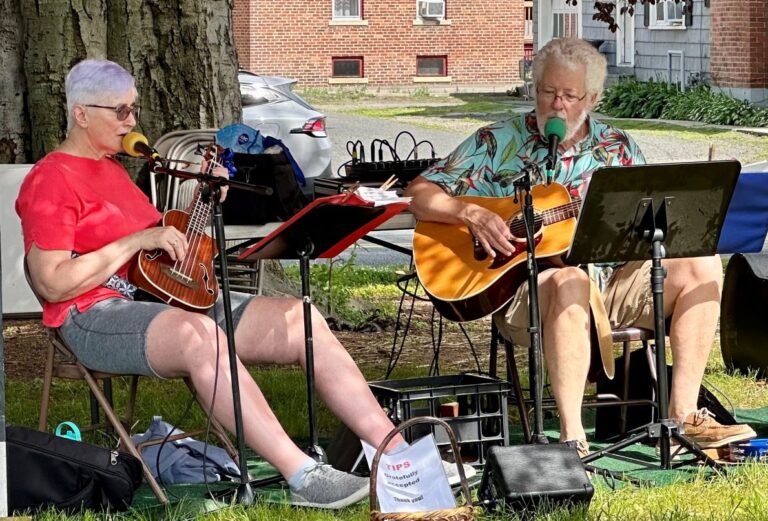 Woman and man playing guitars and singing