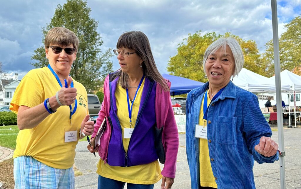 three smiling women wearing yellow shirts