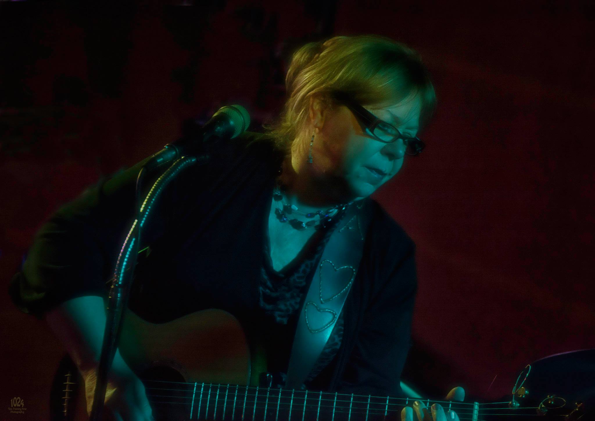 Woman wearing glasses and playing the guitar