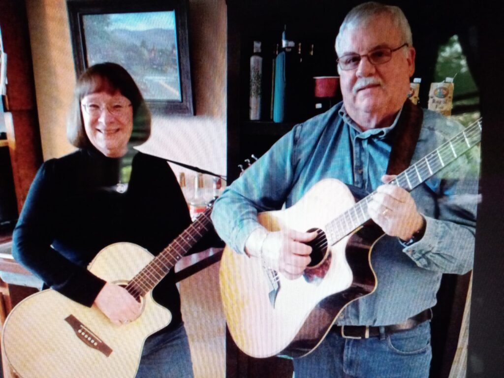 Smiling woman and man each holding an acoustic guitar